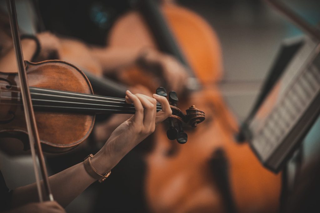 Closeup of a musician playing a violin in an orchestra.